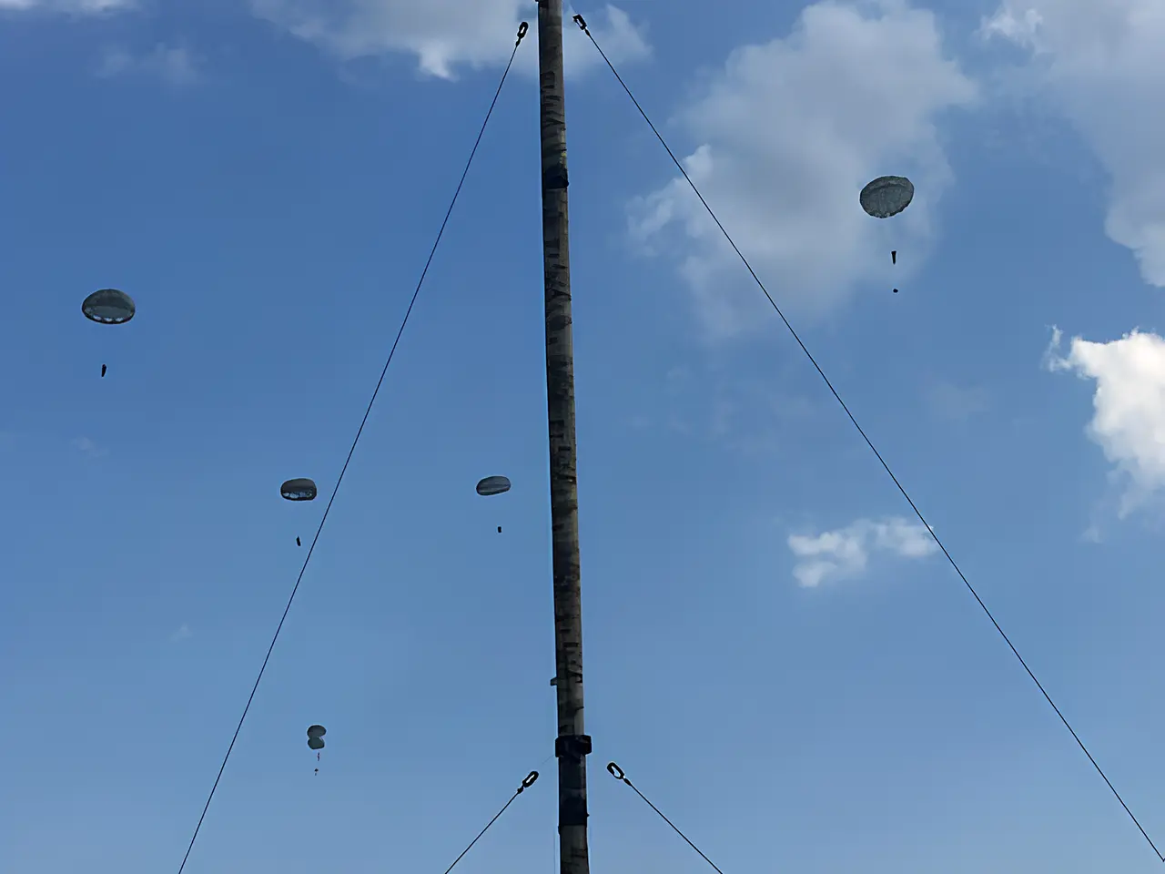 Antenna mast with paratroopers descending in the background