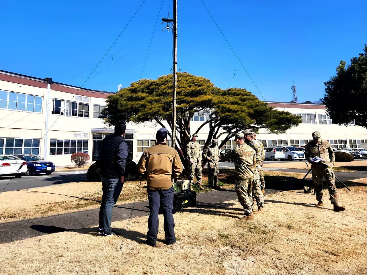 Soldiers raising an antenna mast during a field exercise