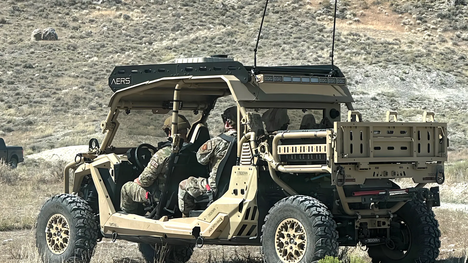 Tactical utility vehicle with roof-mounted antennas and integrated communications equipment in mountainous terrain